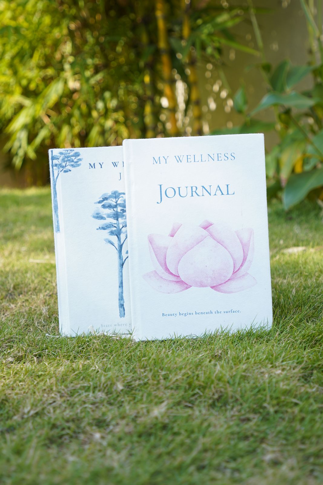 The Pine and Lotus My Wellness Journals standing on the grass in a garden